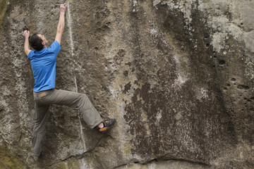 Athlete climbs on rock with rope.