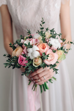 Beautiful wedding bouquet in hands of the bride. Peony rose, cotton, roses. Pink and Peach. Trendy and modern wedding flowers. Ideal photo for commercial. 
