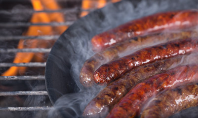 Grilling sausages on barbecue grill.