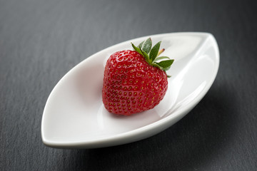 A ripe strawberry in a leaf-shaped plate, minimalist style food