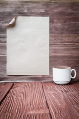 Cup of coffee with paper sheet over vintage wooden background