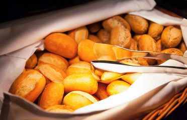 Hot fresh bread in a basket with tongs