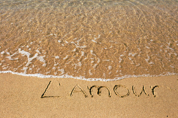 Inscription L'amour (love in french) at the sand on the summer beach