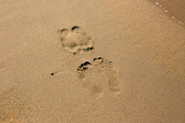 Traces of two human feets on the summer beach