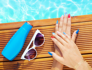 Woman lying down by the pool, marine sailor gel nails close up summer beauty concept