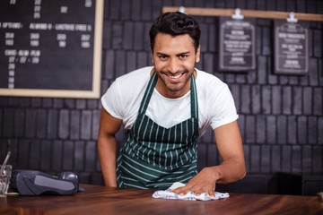 Smiling barista cleaning counter
