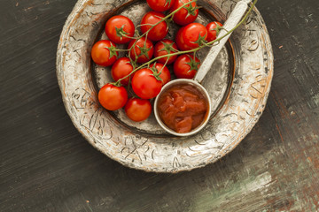 Bunch tomatoes and sauce on wooden background