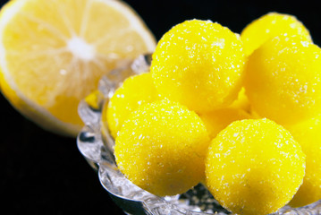 Lemon candies and a slice of a lemon on the dark background