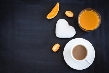 Obraz na płótnie Canvas Black coffee, orange juice, cakes in the shape of a heart and kumquat on a black background