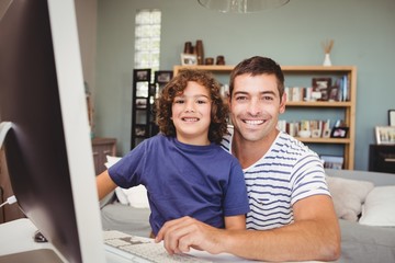 Portrait of cheerful father and son using computer