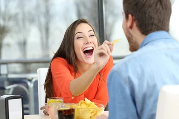 Schilderijen op glas Playful couple eating chip potatoes © Antonioguillem