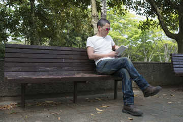 Obraz premium 公園のベンチで本を読む男性