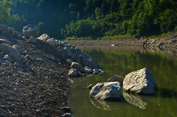 Rocks fallen into water of Uvac river at sunny summer morning, southwest Serbia