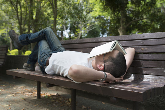 公園のベンチで昼寝をする男性