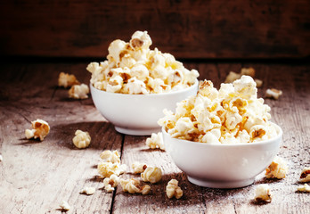 Sweet popcorn in white bowls, vintage wooden background, selecti