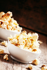 Sweet popcorn in white bowls, vintage wooden background, selecti