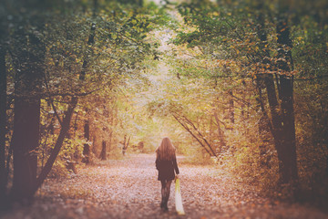 Woman walking away on forest autumn road