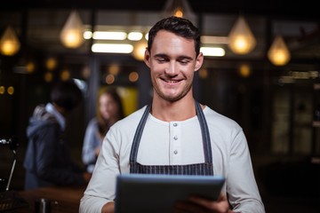 Smiling barista using tablet