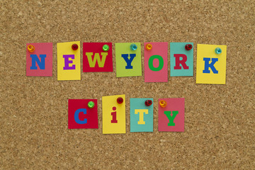 New York city written on colorful notes pinned on cork board.