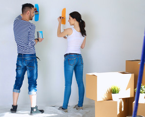 Portrait of happy smiling young couple  painting interior wall of new house