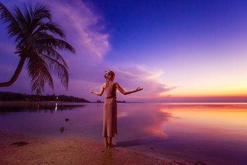 Fototapeta premium Young woman is standing relaxed at deep blue tropical sunset