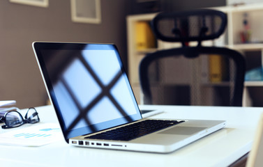 Office workplace with laptop on wood table against the windows