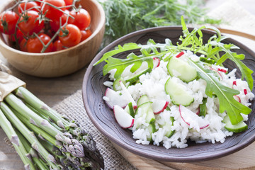Risotto with fresh cucumber and radishes around fresh green asparagus spears