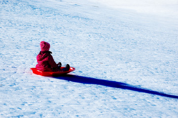 Fototapeta na wymiar Kids Sledding Down Snow Hill on Sled Fast Speed