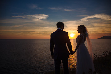 silhouette of a groom and bride on background of ocean at beautiful sunset
