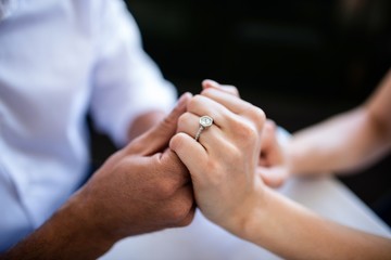 Close-up of couple holding hands with engagement ring - obrazy, fototapety, plakaty