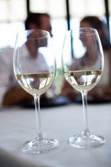 Close up of two wine glasses and couple in background