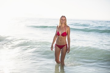 Obraz premium Young woman in bikini standing in water