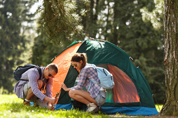Young campers setting up the tent at the forest.