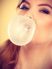 Blonde girl chewing gum making balloon.