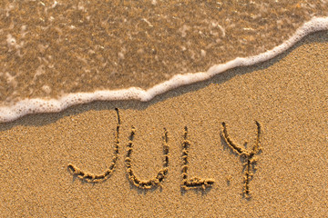 Fototapeta na wymiar July - word drawn on the sand beach with the soft wave. Months series of 12 pictures.
