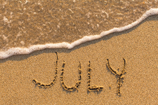 July - word drawn on the sand beach with the soft wave. Months series of 12 pictures.