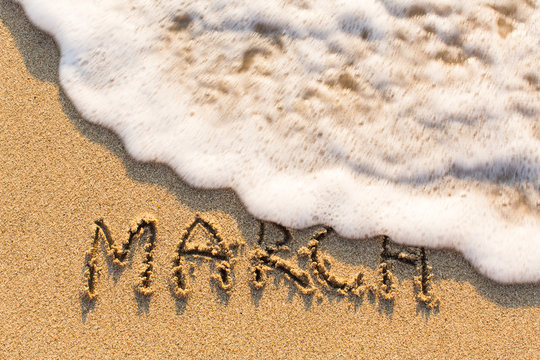March - word drawn on the sand beach with the soft wave. Months series of 12 pictures.
