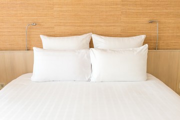 A white bed with 4 pillows and 2 head lights