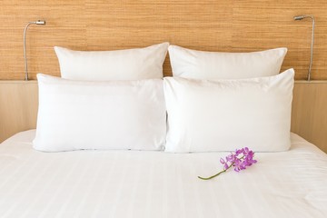A white bed with 4 pillows and 2 head lights
