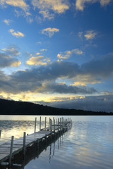 Obraz premium Sunset On The Lake - Traditional wooden dock and its beautiful reflection in the water in the sunset