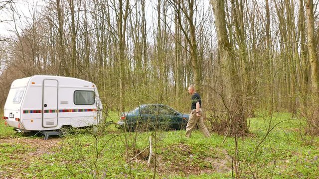 Life in  trailer in wood .  Adult  Man  go near caravan and car .4K shot. 