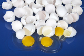 Many broken eggs on a blue reflective table