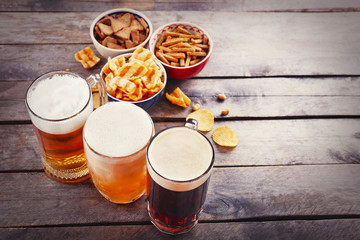 Various types of beer and snacks on wooden table. Retro stylization