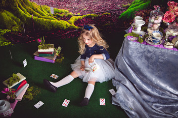 Little girl as Alice in Wonderland pouring tea