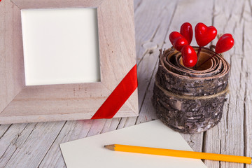 Frame with ribbon, pencil, hearts and a blank sheet