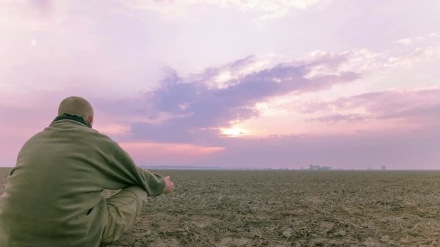 Man meditates in field sunset time .4K Time lapse. RAW output, without birds.

