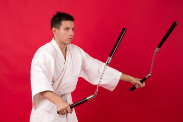 Man in kimono practicing martial arts. Master display nunchaku kata. 