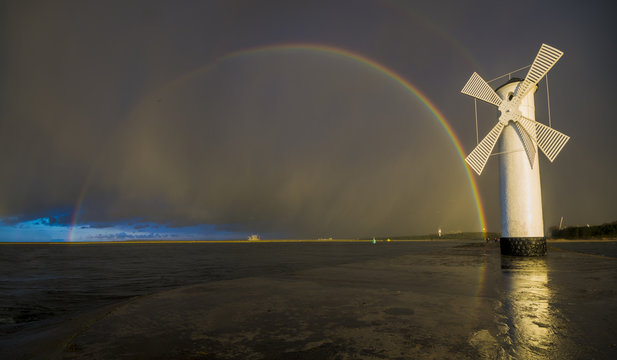 Fototapeta Tęcza nad wiatrakiem po przejściu wieczornej burzy nad morzem