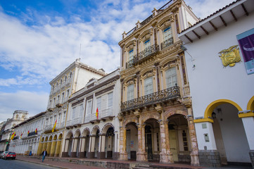 Fototapeta na wymiar Cuenca, Ecuador - April 22, 2015: Beautiful spanish colonial townhouses with decorated facades, traditional Cuenca architecture and charm, offical city flags hanging