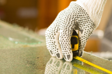 Closeup hand wearing white work gloves using measure tool on transparent piece of glass